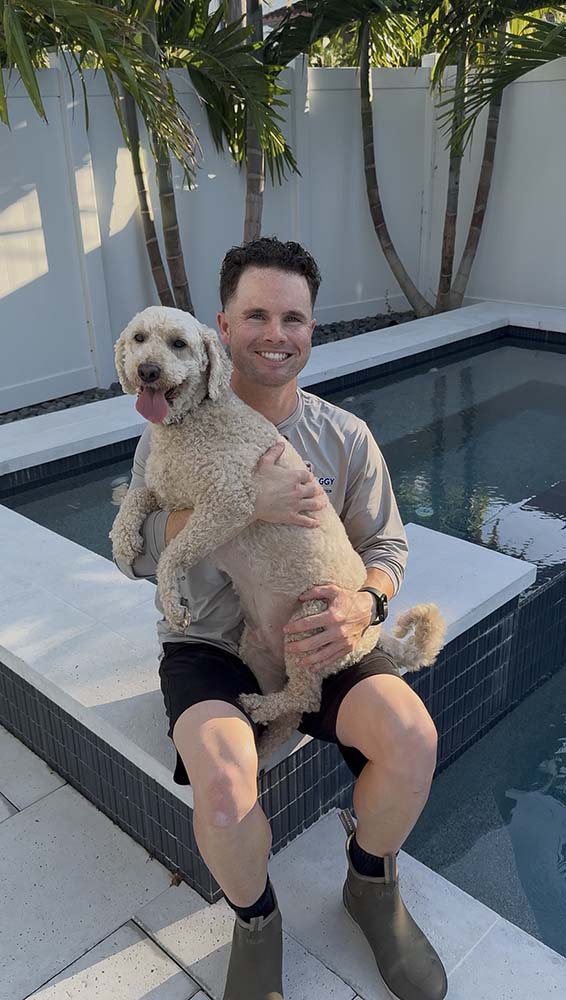 Stephen, owner of Oh Doggy Pools, holding his dog beside a pool in St. Petersburg FL